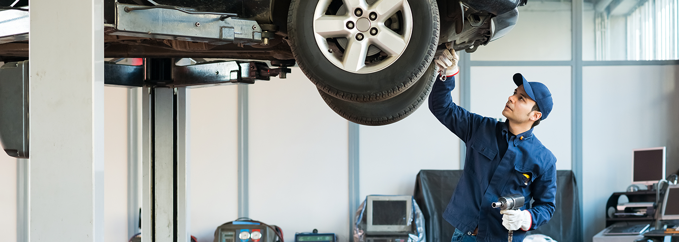 A technician performing express service on a lifted vehicle
