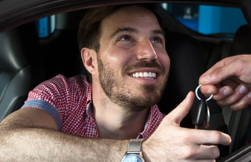 A man receiving rental car keys from a dealership