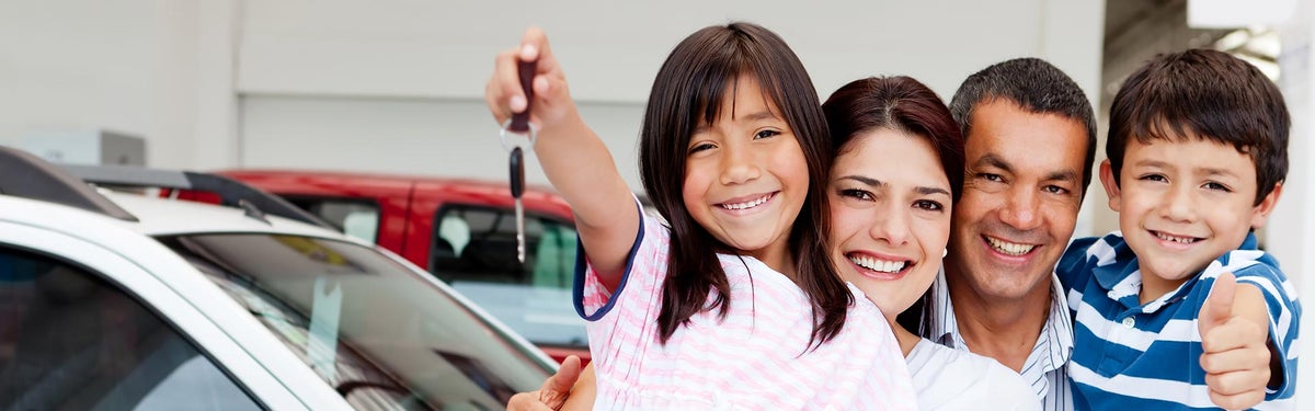 A happy family holding up keys to their lifetime warrantied car